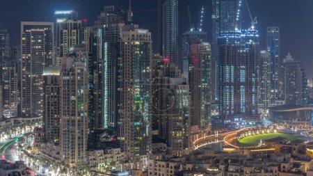 Foto de Futuristic aerial cityscape during all night  with illuminated architecture of Dubai downtown with lights turning off. Many tall skyscrapers and towers. New construction site. United Arab Emirates. - Imagen libre de derechos