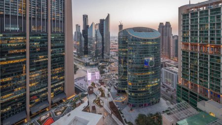 Photo for Dubai international financial center skyscrapers aerial day to night transition . Illuminated towers and promenade on gate avenue panoramic view from above - Royalty Free Image