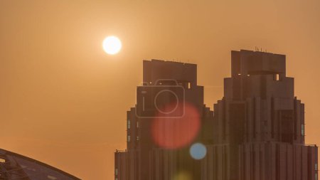 Téléchargez les photos : Sunset over Dubai international financial center skyscrapers aerial . Sun goes down behind tall towers and orange sky on a background - en image libre de droit