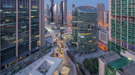 Foto de Dubai international financial center skyscrapers aerial night to day transition . Illuminated towers and walking area on a gate avenue panormic view from above before sunrise - Imagen libre de derechos