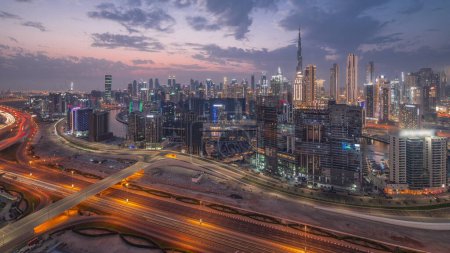 Photo for Skyline with modern architecture of Dubai business bay towers and downtown skyscrapers day to night transition . Aerial view with canal and construction site after sunset - Royalty Free Image