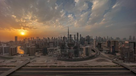 Téléchargez les photos : Sunset over panoramic skyline of Dubai with business bay and downtown district . Aerial view of many modern skyscrapers with colorful clouds and rays of light. United Arab Emirates. - en image libre de droit
