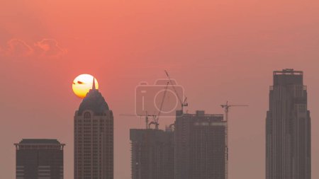 Photo for Skyline with modern architecture of Dubai business bay towers at sunset . Aerial close up view with canal and construction site. Sun setting behind skyscraper - Royalty Free Image