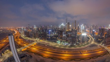 Téléchargez les photos : Panoramic skyline of Dubai with business bay and downtown district night to day transition . Aerial wide angle view of many modern skyscrapers during sunrise with reflections from glass. United Arab Emirates. - en image libre de droit