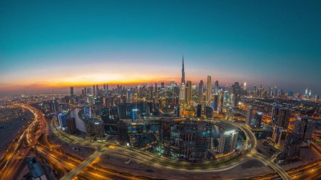 Téléchargez les photos : Panoramic skyline of Dubai with business bay and downtown district day to night . Aerial wide angle view of many modern skyscrapers with traffic on al khail road after sunset. - en image libre de droit
