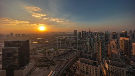 Téléchargez les photos : Sunrise over Dubai marina and JLT skyscrapers along Sheikh Zayed Road aerial morning . Residential and office buildings from above. Orange sky above golf course - en image libre de droit