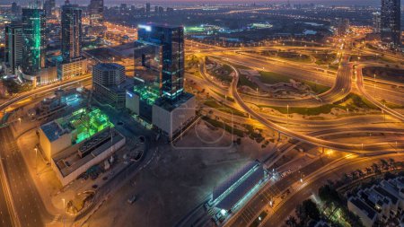 Foto de Aerial panoramic view of media city and al barsha heights district with golf course night to day transition  from Dubai marina during sunrise. Towers and skyscrapers with traffic on a highway crossroad from above - Imagen libre de derechos