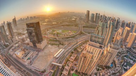 Téléchargez les photos : Sunrise panorama over Dubai marina and JLT skyscrapers along Sheikh Zayed Road aerial morning . Residential and office buildings in media city from above. Orange sky above golf course - en image libre de droit