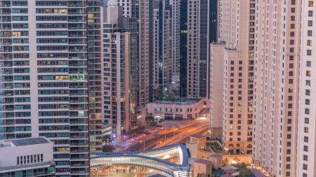 Foto de Overview to JBR and Dubai Marina skyline with modern high rise skyscrapers waterfront living apartments aerial night to day transition . Traffic on road intersection and footbridge - Imagen libre de derechos