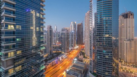 Foto de View of the Dubai Marina and JBR area and traffic on the street aerial night to day transition  and illuminated skyscrapers before sunrise - Imagen libre de derechos
