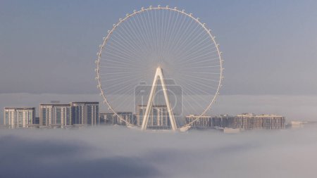 Foto de Bluewaters island with modern architecture and ferris wheel covered by morning fog aerial . New leisure and residential area near Dubai marina and JBR after sunrise - Imagen libre de derechos
