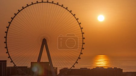 Téléchargez les photos : Sunset over Bluewaters island with modern architecture and ferris wheel aerial  close up view. New leisure and residential area near Dubai marina and JBR. Orange sky - en image libre de droit