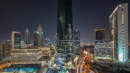 Foto de Dubai International Financial district during all night . Panoramic aerial view of business office towers with lights turning off. Illuminated skyscrapers with hotels near downtown - Imagen libre de derechos