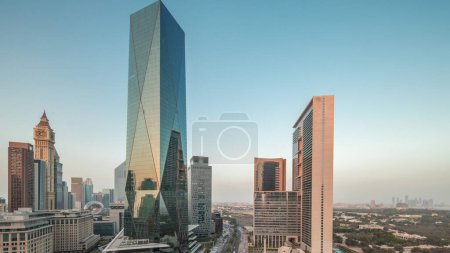 Foto de Dubai International Financial district day to night transition . Panoramic aerial view of business office towers after sunset. Skyscrapers with hotels and traffic on a road near downtown - Imagen libre de derechos