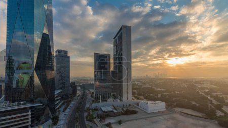 Photo for Sunrise in Dubai International Financial district transition . Panoramic aerial view of business office towers at morning. Skyscrapers with hotels and shopping malls near downtown - Royalty Free Image