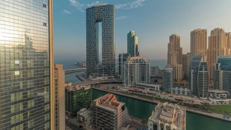 Foto de Dubai Marina skyscrapers and JBR district during sunrise with sun reflected from luxury buildings and resorts aerial . Waterfront with palms and boats floating in canal - Imagen libre de derechos