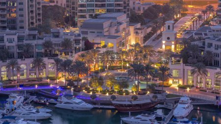 Foto de Picturesque fountain on Dubai Marina promenade aerial night to day transition  with palm around and yachts in harbor before sunrise - Imagen libre de derechos