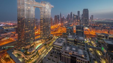 Foto de Futuristic Dubai Downtown and finansial district skyline aerial night to day transition . Many towers and skyscrapers with traffic on streets during sunrise with sun reflections - Imagen libre de derechos