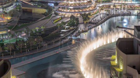 Téléchargez les photos : Dubai promenade singing fountains on the background of architecture aerial . People watching show near shopping mall - en image libre de droit