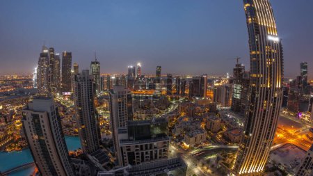 Téléchargez les photos : Aerial panorama of a big futuristic city night to day transition . Business bay and Downtown district before sunrise with skyscrapers and traditional houses, Dubai, United Arab Emirates skyline. - en image libre de droit
