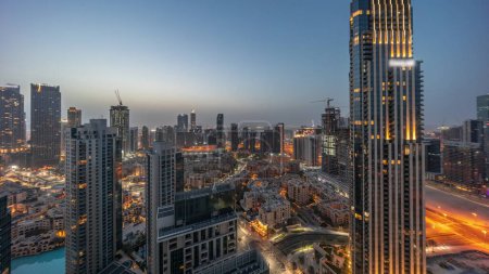 Foto de Aerial panoramic view of a big futuristic city night to day transition . Business bay and Downtown district before sunrise with skyscrapers and traditional houses, Dubai, United Arab Emirates skyline. - Imagen libre de derechos