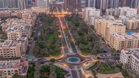 Téléchargez les photos : Low rise buildings in Greens district aerial day to night transition . Dubai skyline with palms and trees. Traffic on a road intersection - en image libre de droit