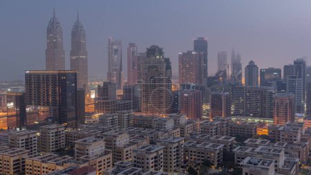 Foto de Skyscrapers in Barsha Heights district and low rise buildings in Greens district aerial night to day transition . Dubai skyline with internet city covered by morning fog - Imagen libre de derechos