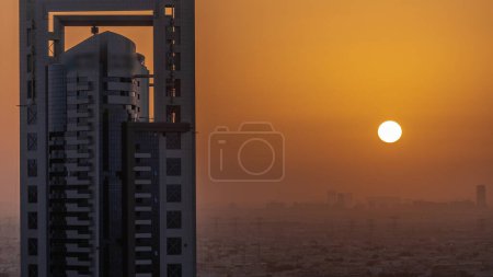 Foto de Sunrise over skyscrapers in Barsha Heights district and villa houses with power lines aerial . Dubai urban skyline with orange sky at morning - Imagen libre de derechos