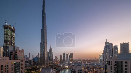 Foto de Dubai Downtown panoramic cityscape with tallest skyscrapers around aerial night to day transition . Construction site of new towers and busy roads with traffic from above - Imagen libre de derechos