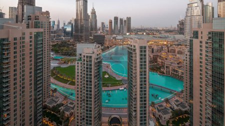 Photo for Dubai Downtown cityscape with tallest skyscrapers around fountain aerial day to night transition . Park with lake and walking area from above - Royalty Free Image