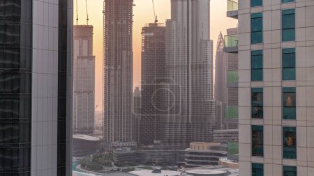 Téléchargez les photos : Shopping mall exterior with reastaurants  at sunset in Dubai, United Arab Emirates. Aerial top view with tallest skyscrapers under construction on a background - en image libre de droit