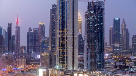 Téléchargez les photos : Row of the tall buildings around Sheikh Zayed Road and DIFC district aerial day to night transition panoramic  in Dubai, UAE. International Financial Centre skyscrapers with glass surface - en image libre de droit