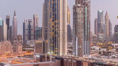 Téléchargez les photos : Panorama of tall buildings around Sheikh Zayed Road and DIFC district aerial night to day transition  in Dubai, UAE. International Financial Centre skyscrapers with glass surface before sunrise - en image libre de droit