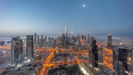 Foto de Aerial view of tallest towers in Dubai Downtown skyline night to day transition  before sunrise. Financial district and business area in smart urban city with Moon. Skyscraper and high-rise buildings - Imagen libre de derechos