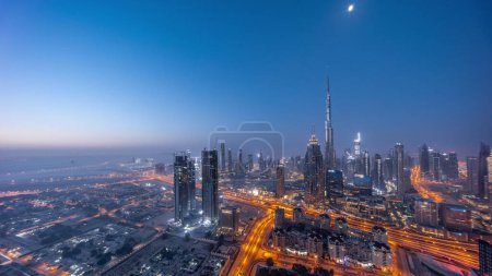Téléchargez les photos : Aerial panoramic view of tallest towers in Dubai Downtown skyline night to day transition  before sunrise. Financial district and business area in smart urban city. Skyscraper and high-rise buildings - en image libre de droit