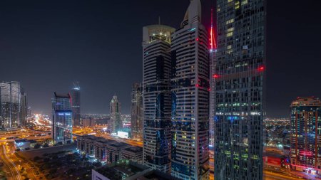 Foto de Aerial view of Dubai International Financial District with many skyscrapers night . Starry sky and illumination turning off. Dubai, UAE. - Imagen libre de derechos