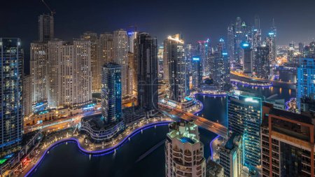 Photo for View of various skyscrapers in tallest recidential block in Dubai Marina aerial night  with artificial canal. Many towers with flashing lights in windows and yachts trails - Royalty Free Image