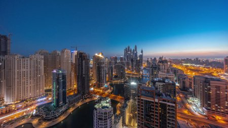 Téléchargez les photos : Panorama of various skyscrapers in tallest recidential block in Dubai Marina aerial night to day transition  with artificial canal. Many towers in JBR district and yachts before sunrise - en image libre de droit