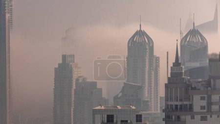Téléchargez les photos : Dubai Marina and Media City districts with morning fog between modern skyscrapers and office buildings during sunrise aerial . Traffic on overpass and road intersection - en image libre de droit