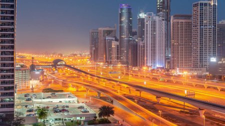 Foto de Dubai Marina skyscrapers and Sheikh Zayed road with metro railway aerial night to day transition . Traffic on a highway near modern towers before sunrise, United Arab Emirates - Imagen libre de derechos