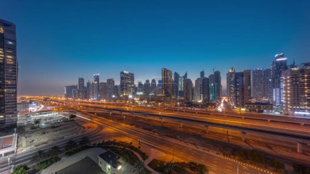 Téléchargez les photos : Dubai Marina skyscrapers panorama and Sheikh Zayed road with metro railway aerial day to night transition . Traffic on a highway near modern towers after sunset, United Arab Emirates - en image libre de droit