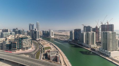 Téléchargez les photos : Des gratte-ciels et des tours à l'antenne de Business Bay pendant toute la journée, avec des ombres qui se déplacent rapidement à Dubaï, aux Émirats arabes unis. Vue panoramique d'en haut avec canal - en image libre de droit