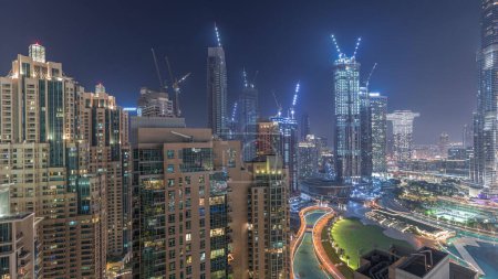 Téléchargez les photos : Panorama du centre-ville de Dubaï timelapse de nuit aérienne. Skyline urbaine de la baie d'affaires avec des gratte-ciel modernes et des tours chantier de construction d'en haut - en image libre de droit