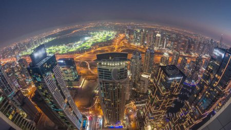 Photo for Panorama of Dubai Marina with JLT skyscrapers and golf course day to night transition timelapse, Dubai, United Arab Emirates. Aerial view from above towers after sunset - Royalty Free Image