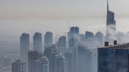 Téléchargez les photos : Le brouillard couvrait les gratte-ciel du quartier JLT. Vue de dessus depuis les tours de la marina de Dubaï le soir - en image libre de droit