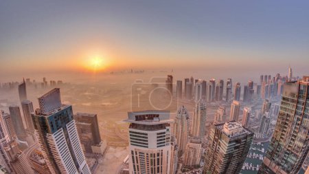 Foto de Panorama de Dubai Marina con rascacielos JLT y campo de golf durante el amanecer timelapse, Dubai, Emiratos Árabes Unidos. Vista aérea desde las torres de arriba mañana brumosa. skyline de la ciudad con tejados - Imagen libre de derechos