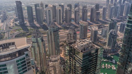 Téléchargez les photos : JLT et Dubai Marina gratte-ciel recoupés par Sheikh Zayed Road pendant toute la journée. Vue aérienne du dessus avec des ombres se déplaçant rapidement et la circulation sur l'autoroute - en image libre de droit