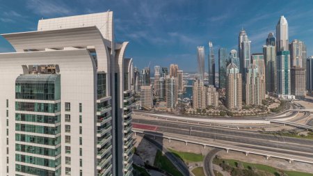 Téléchargez les photos : Panorama montrant Dubai Marina et la ville des médias avec parcours de golf carrefour autoroute spaghetti jonction timelapse. Les plus hauts gratte-ciel et la circulation. Vue aérienne du quartier JLT - en image libre de droit