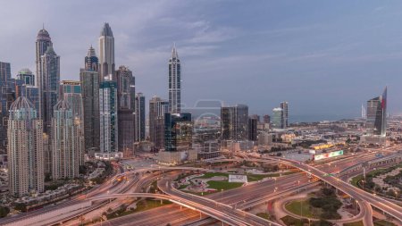 Téléchargez les photos : Panorama du port de plaisance de Dubaï et de l'intersection des autoroutes médiatiques et des spaghettis nuit après coucher du soleil. Les gratte-ciel les plus hauts éclairés sur un fond. Vue aérienne du quartier JLT. - en image libre de droit