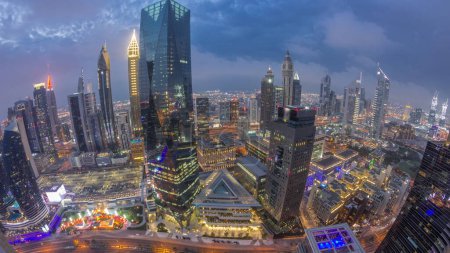 Photo for Panorama of futuristic skyscrapers after sunset in financial district business center in Dubai with traffic on a road day to night transition timelapse. Aerial view from above with cloudy sky - Royalty Free Image